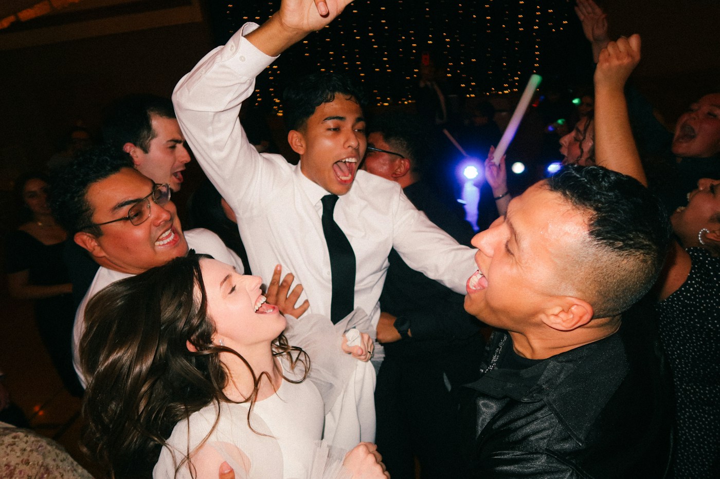 Wedding guests cheering and dancing together at a reception